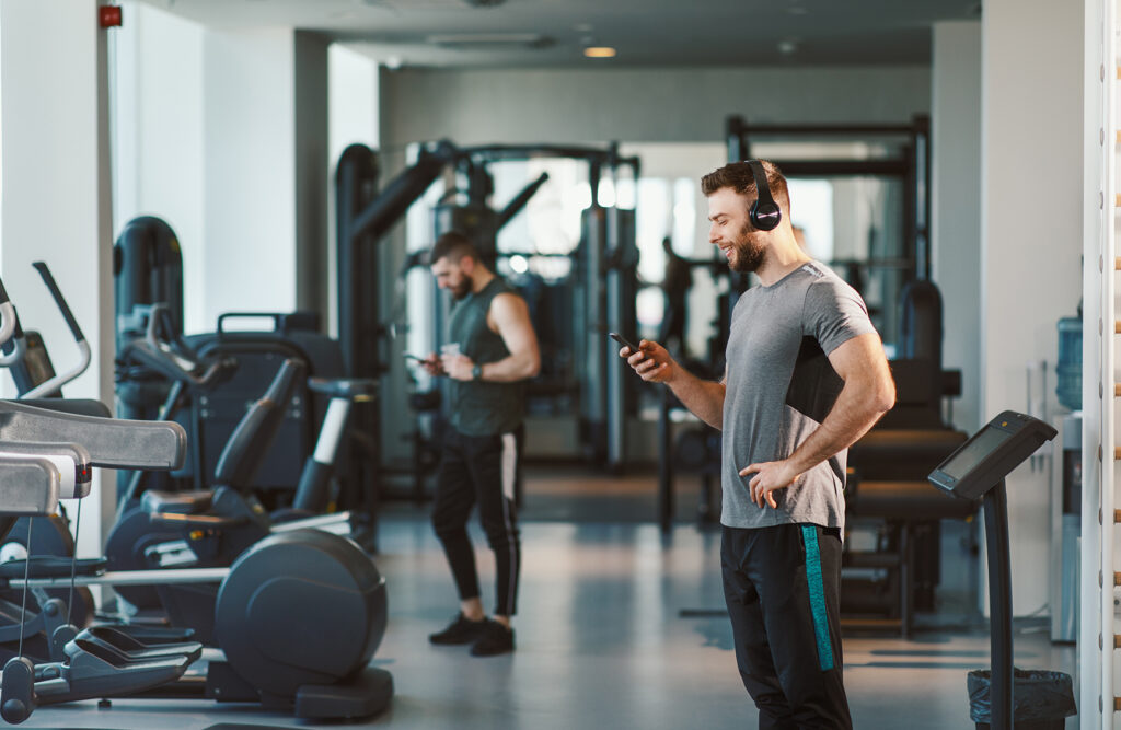 Young man prepares to workout at the gym and chooses music on a smartphone